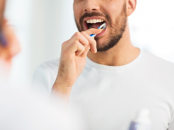 Man smiling while brushing his teeth