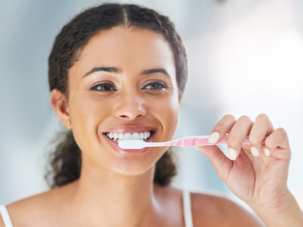 Closeup of woman smiling while brushing her teeth