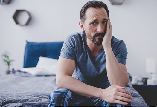 Man wincing in pain and holding the side of his face