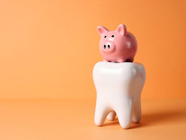 Pink piggy bank on large model tooth with orange background
