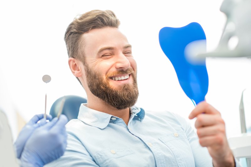 Patient smiling in mirror after replacing metal fillings